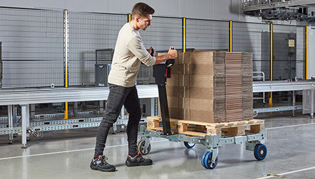 Leichte, intuitive Bedienung für optimale Unterstützung. Mann schiebt Transportwagen mit Pappen beladen