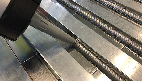 Aluminium-Profil wird mit silberfarbenem Klebstoff mittels einer Dosierpumpe versehen.